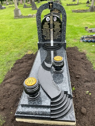 Blue Pearl and Black Granite gates of heaven headstone upon kerb set with cover slab, external path/steps, curved steps and two turned vases.
