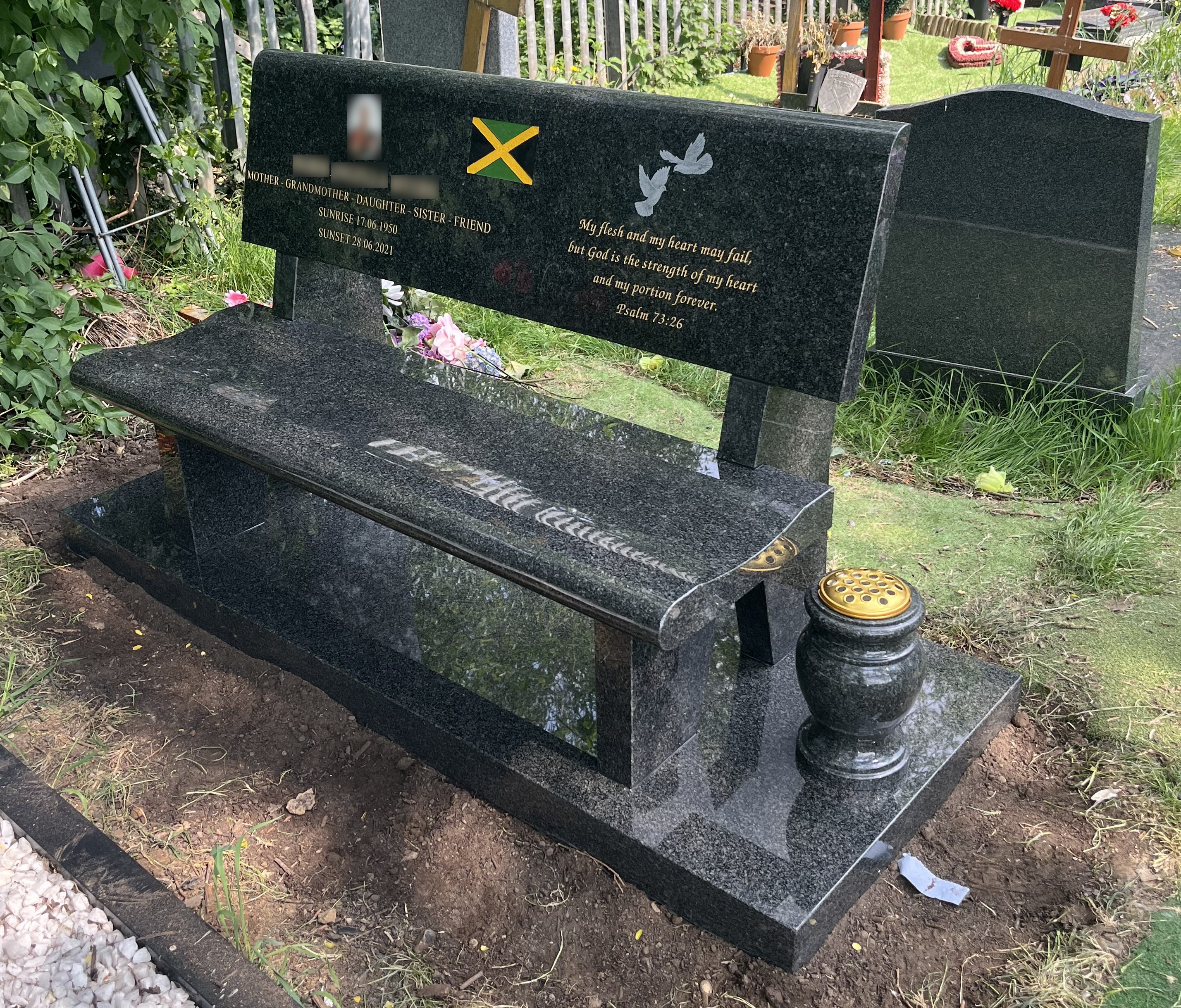 Dark grey granite bench with offset vase and a granite foundation piece