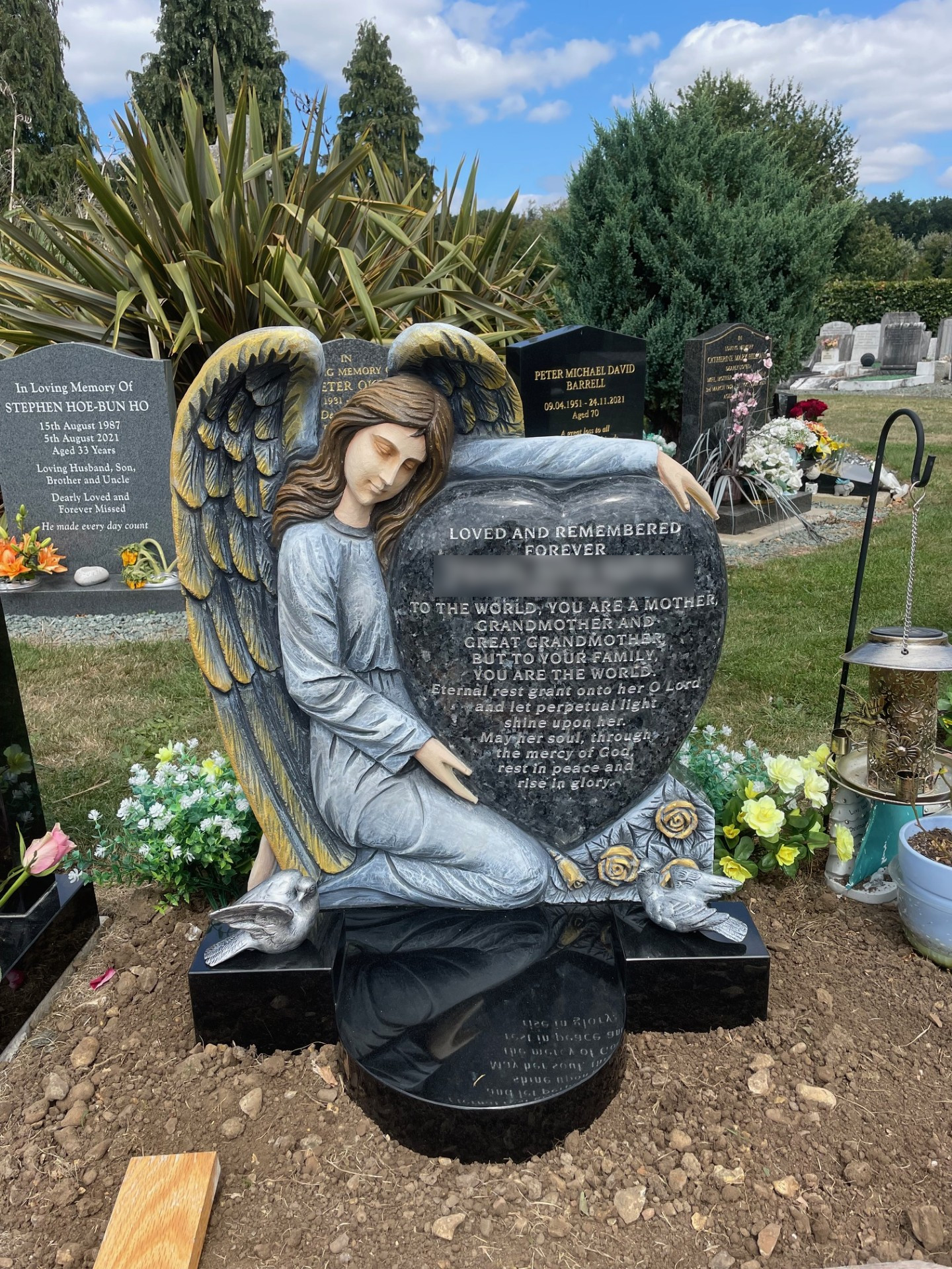 Blue Pearl granite hand carved painted Angel holding a cushioned heart lawn memorial.