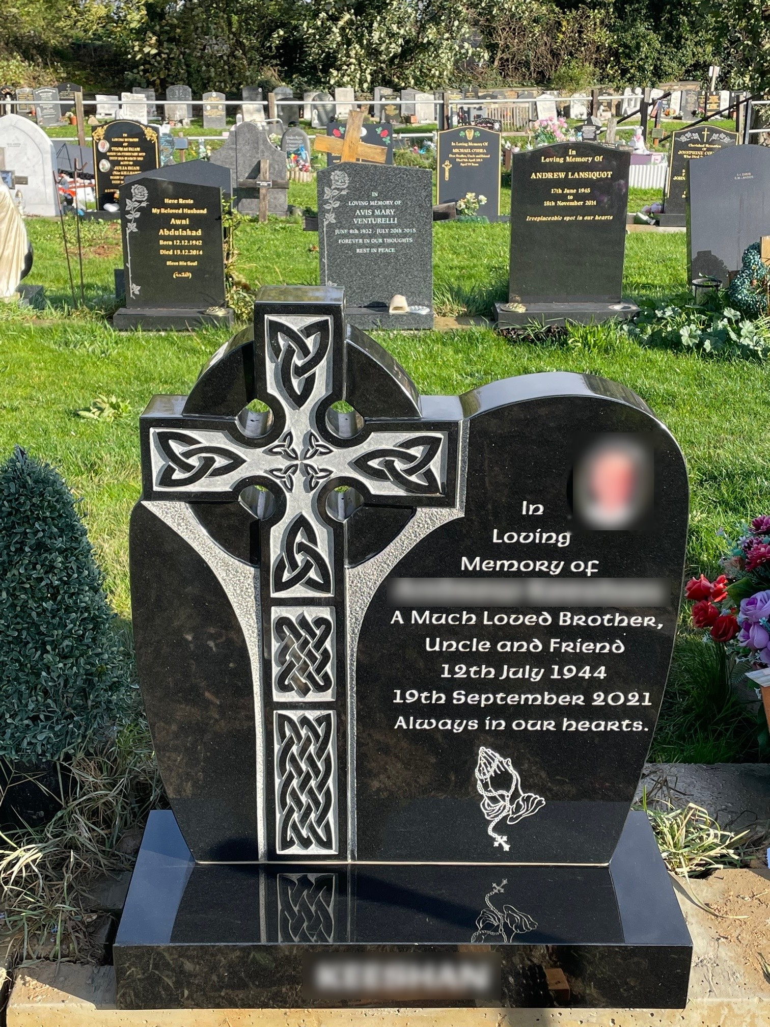 Black granite Celtic Cross lawn memorial with relief carving.