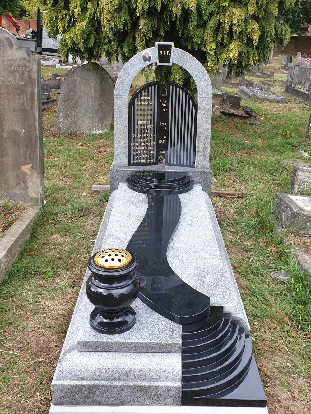 Black and Light Grey Granite gates of heaven headstone with cover slab, external path/steps, curved steps and one turned vase.